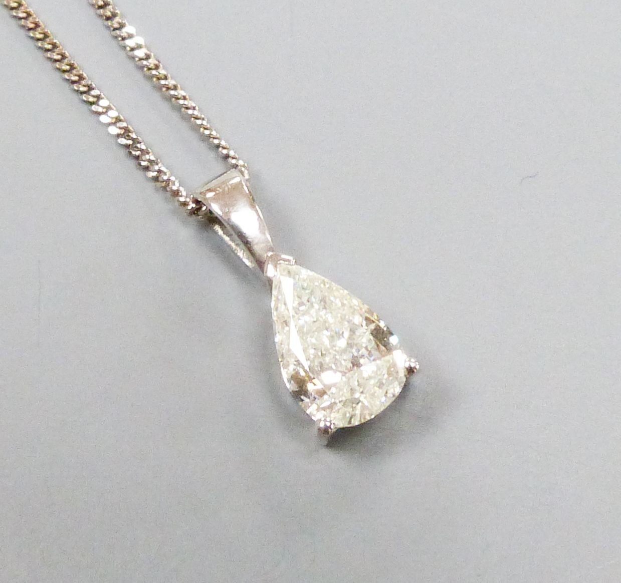 A modern white metal and solitaire pear shaped diamond set pendant, overall 14mm, on and 18ct white gold fine link chain, 40cm, gross weight 2.9 grams